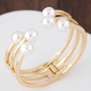Détail d'un bracelet doré multicouche avec six perles et un fermoir à charnière sûr