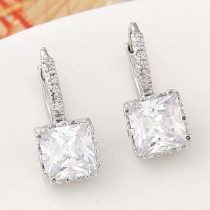Macro detail of square zircon earrings with silver beaded edges and claw setting