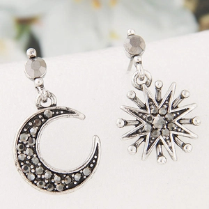 Asymmetric crescent moon and sun stud earrings with shimmering stones in vintage silver finish