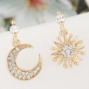 Macro detail of asymmetric moon and sunburst stud earrings with pavé crystal settings