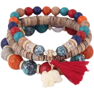 Detail of bohemian layered bracelet with multicolored beads, red tassel and elephant charm