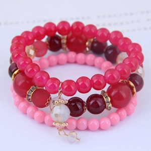 Detail of pink and red beaded bracelets with crystal pendants and gold-tone spacers