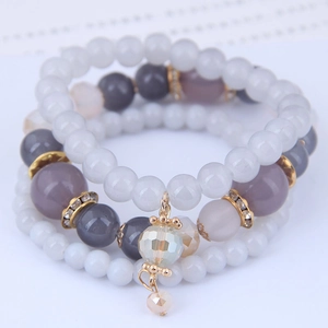 Detail of multi-layered beaded bracelet set with crystal charms and tassel in soft tones