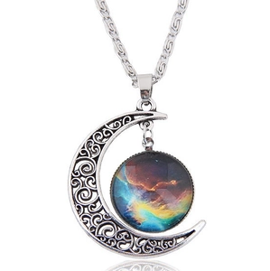 Detail of silver crescent moon pendant with intricate filigree and colorful nebula galaxy stone