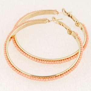 Macro shot of gold-plated hoop earrings featuring pink matte beads and pin closure