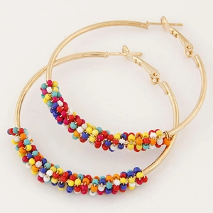Detailed close-up of gold hoop earrings wrapped with vibrant colorful seed beads