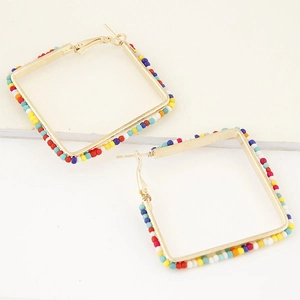 Macro shot of square gold hoop earrings with multi-color seed beads and bohemian pattern