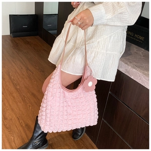 Détail du sac hobo rose à texture popcorn avec breloque fleurie et tissu plissé
