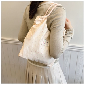 Détail du sac à dos cordon en toile rose à fleurs porté par un mannequin en vue arrière