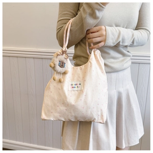 Detail of floral canvas tote bag with pink rabbit print and sheep plush pendant