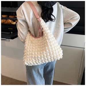 Détail du sac à texture bulles crème avec bandoulière rose et breloque fleurie