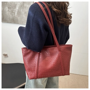 Dettaglio della borsa tote bordeaux con trama intrecciata indossata da una modella