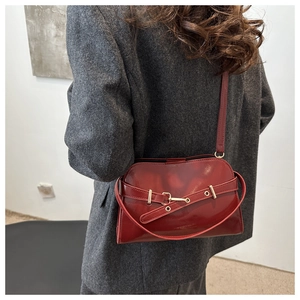 Detail der weinroten Lackleder-Handtasche mit Schnalle, Schultergurt und Glanz-Textur