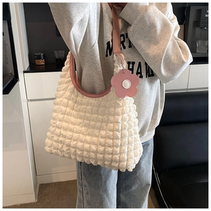 Détail d'un sac blanc à texture bulle avec bandoulière rose et accessoire floral