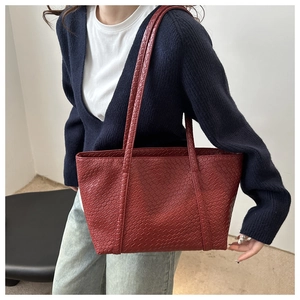 Dettaglio della borsa tote rosso scuro con trama intrecciata e lavorazione in pelle