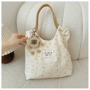 Detail of printed nylon tote bag with lion plush pendant and woven rope handles