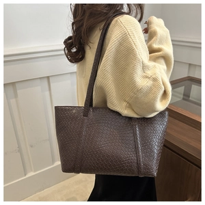 Dettaglio della grande borsa tote intrecciata marrone scuro con trama in pelle sulla spalla