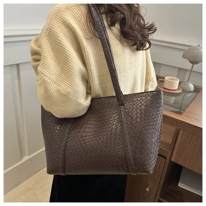 Dettaglio della trama intrecciata in pelle marrone scuro di una borsa tote grande