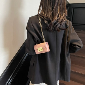 Mini light pink leather chain crossbody bag with gold hardware on a shoulder model