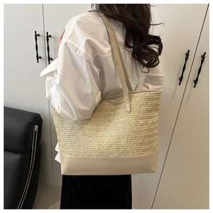 Detail of minimalist beige straw tote bag featuring woven texture and leather straps