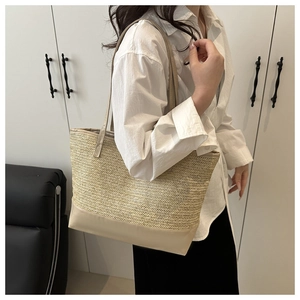 Detail of minimalist khaki woven tote bag with smooth cream leather base and shoulder strap