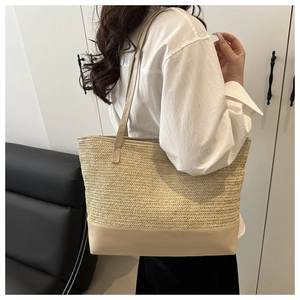 Detail van een grote rieten tas met geweven textuur en beige lederen schouderbanden