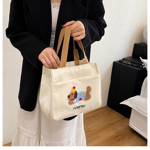 Détail de sac en toile avec un motif de chien brodé en relief et une anse marron