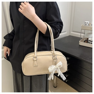 Detail view of cream Boston bag featuring white lace bow and pearl pendant charm