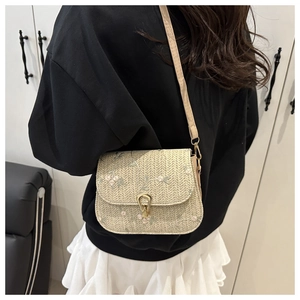 Detail of woven straw crossbody bag with floral embroidery and gold metal clasp