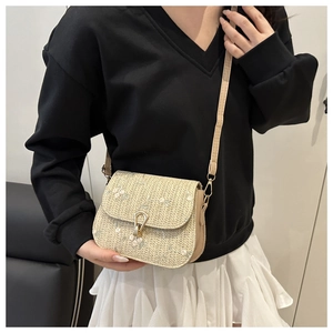 Detail of woven crossbody bag with floral embroidery and gold metal twist lock