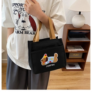 Détail du sac cabas en toile noire avec broderie chien de dessin animé et anses brunes