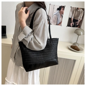 Detail van grote strooien shopper tas met zwart lederen stiksels en lange schouderbanden