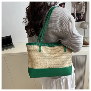 Detail of herringbone woven tote bag with green leather trim and long shoulder handles