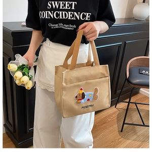 Détail du sac cabas en toile avec écusson chien et anses marron dans un cadre de style