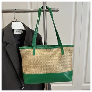 Detail of woven straw texture and green faux leather straps on a summer tote bag
