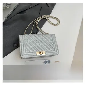 Détail du sac chaîne en cuir matelassé gris avec fermoir en métal et téléphone pour échelle