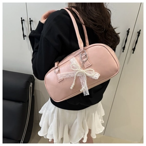 Detail of pink glossy leather Boston bag featuring lace bow and pearl pendant decoration