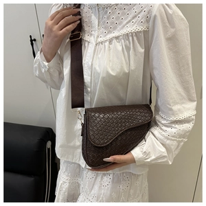Detail of dark brown woven leather saddle bag featuring a wide nylon shoulder strap