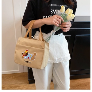 Détail du sac en toile beige avec broderie de teckel, poche frontale et accent tulipe