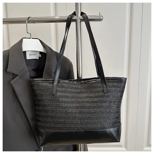 Detail of black woven straw texture and premium leather trim on this large tote bag