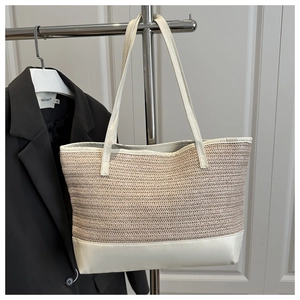 Detailed straw weave pattern and white leather strap of the beige tote bag
