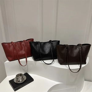 Minimalist woven tote bags in burgundy, black, and coffee on a white display stand