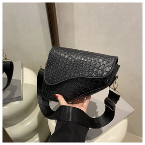 Detail of black woven saddle bag with gold metal buckles and wide nylon shoulder strap
