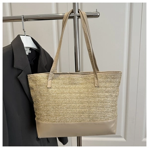 Detail of large woven tote bag featuring wavy straw texture and brown leather straps