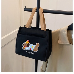 Détail de la broderie bouclée teckel sur sac en toile noire avec des anses de couleur kaki