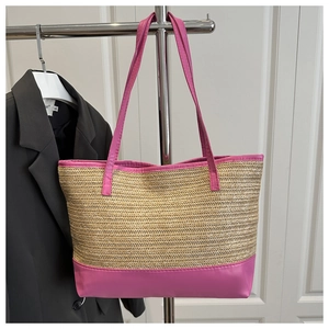 Detail of straw tote bag featuring vibrant fuchsia leather trim and sturdy handles