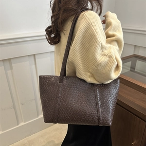 Borsa tote in pelle intrecciata marrone scuro con tracolla indossata da una modella