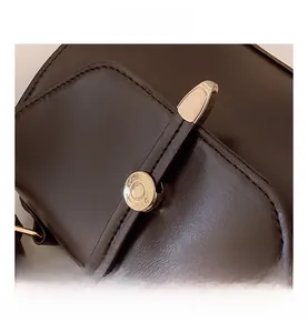 Gros plan détaillé du sac à rabat en cuir noir avec boucle en métal doré élégante