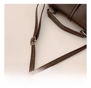Détail de la bandoulière réglable avec boucle en métal doré sur le sac en cuir brun