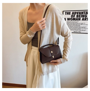 Sac bandoulière en cuir marron foncé mat porté avec un cardigan en maille beige chic